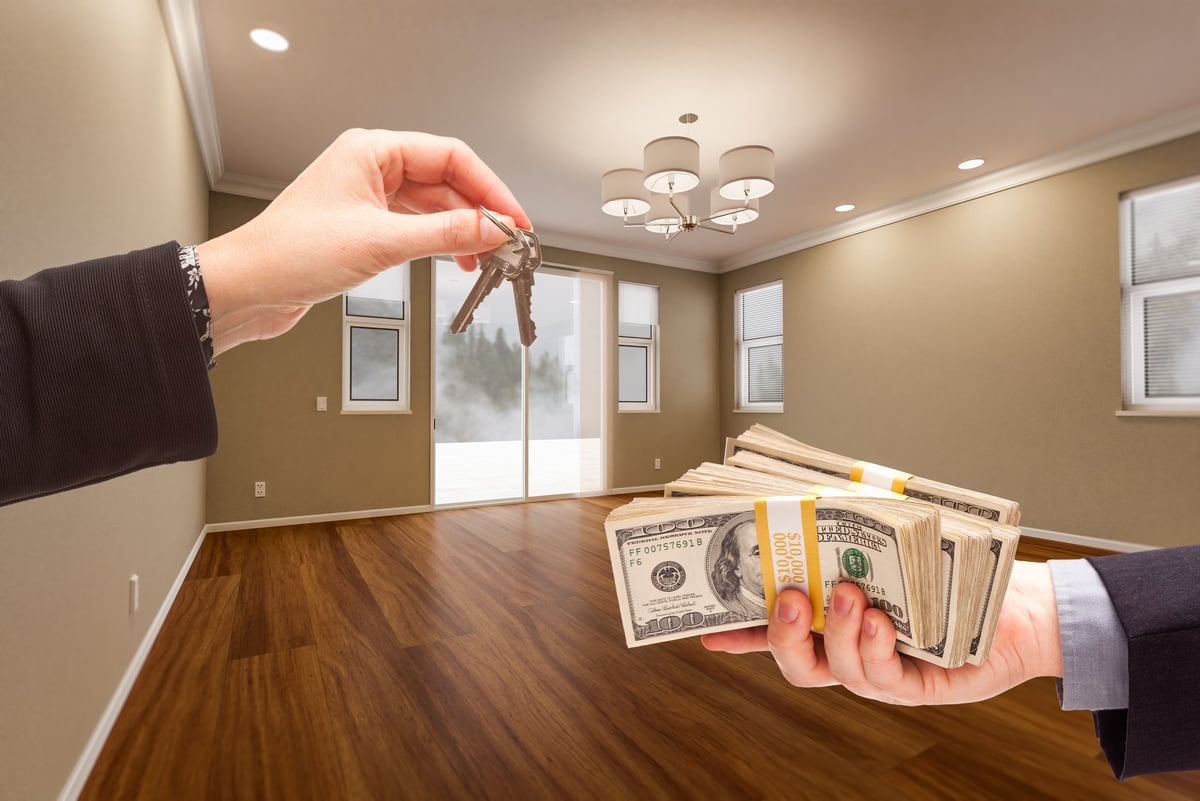 Agent handing over house keys for cash to a happy new homeowner